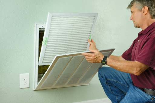 A man replacing an AC air filter in a home.