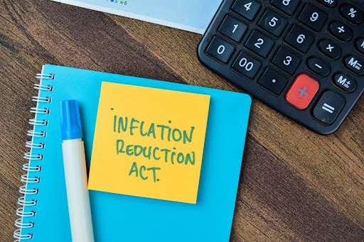 Sticky note reading "Inflation reduction act" next to a calculator.